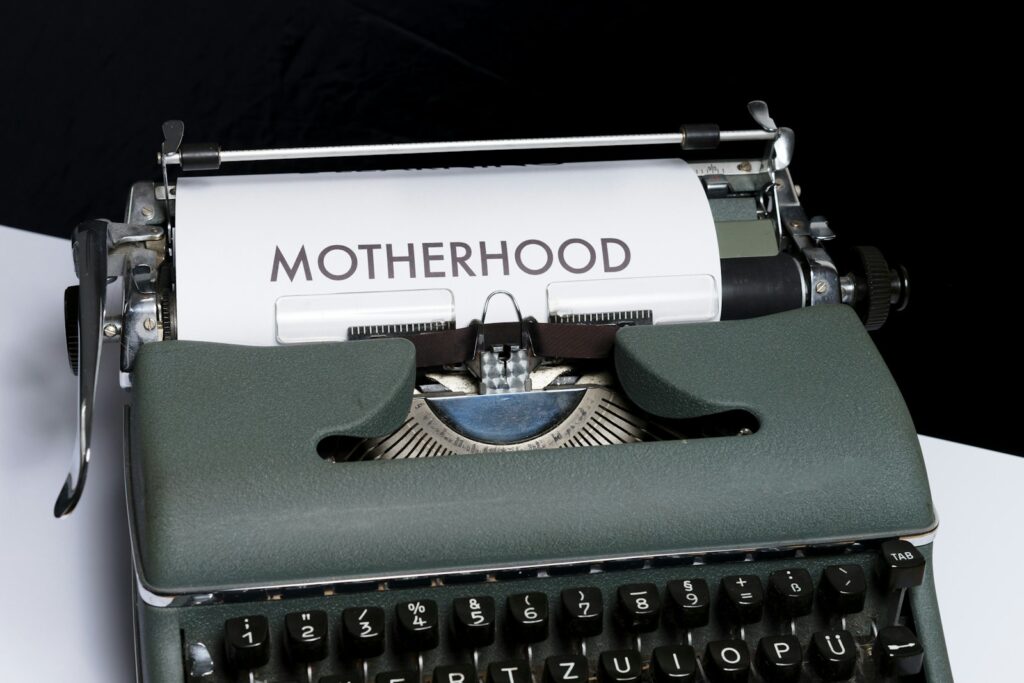 green and white braille typewriter with text 'motherhood' typed