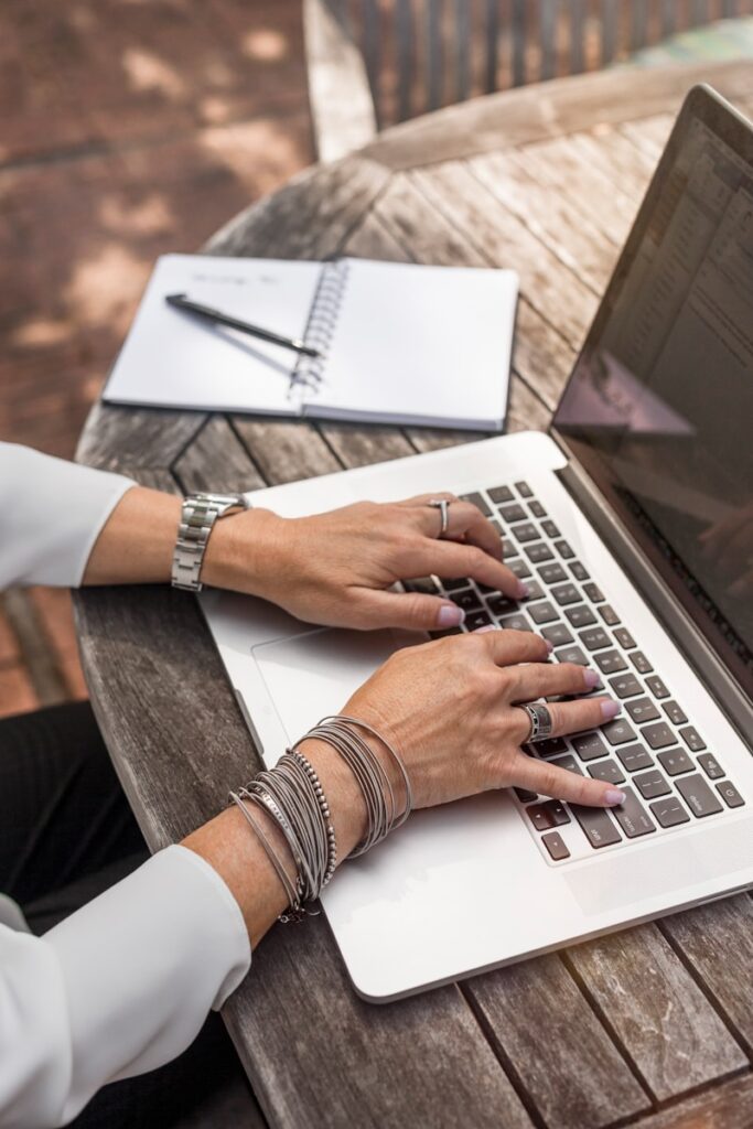 person writing a blog on MacBook Pro on brown wooden table during daytime photo