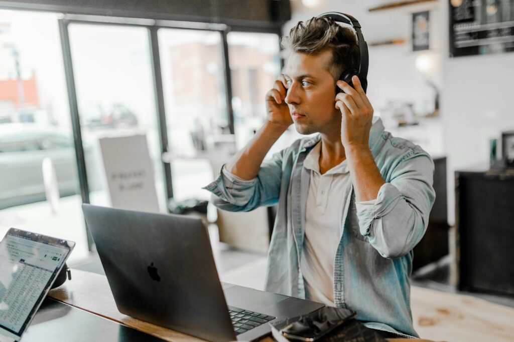 Man near Macbook wearing headphones for virtual assistance tasks