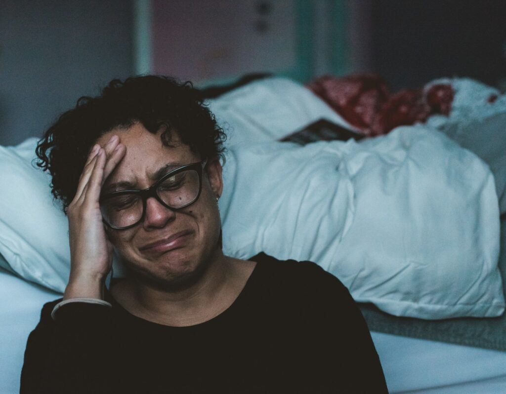 Overwhelmed mother experiencing postpartum depression sitting alone on the floor beside bed